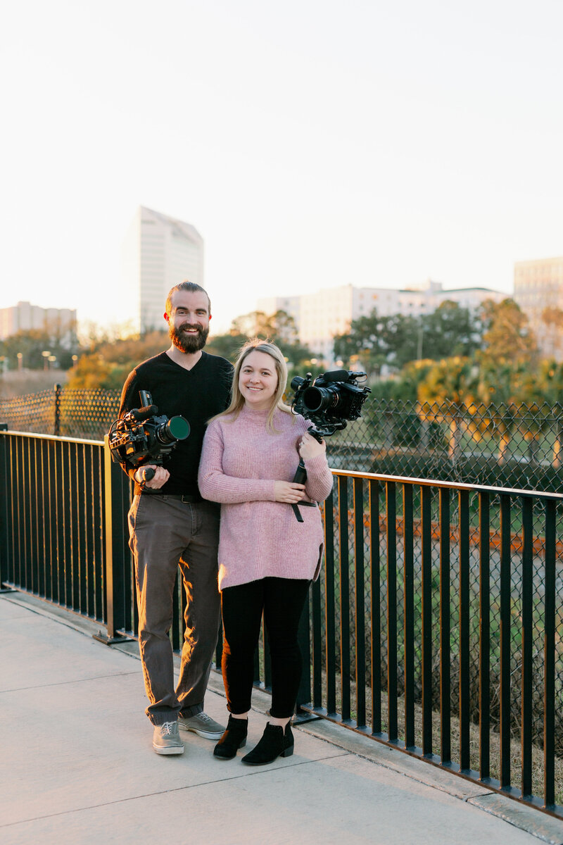 couple holding cameras in front of downtown cityscape