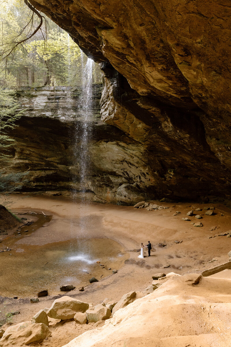 Couple standing next to the waterfall at Ash Cave.