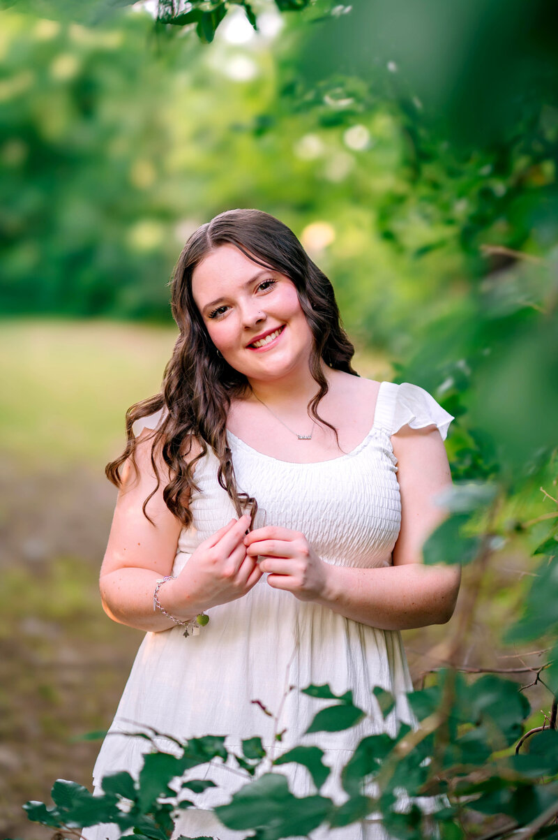 Young woman smiling in a natural outdoor setting during a portrait session in Allen, Texas, photographed by Jennifer L. Kirk Photography.