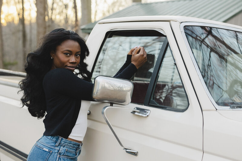 A person leaning up against the window of a pickup truck