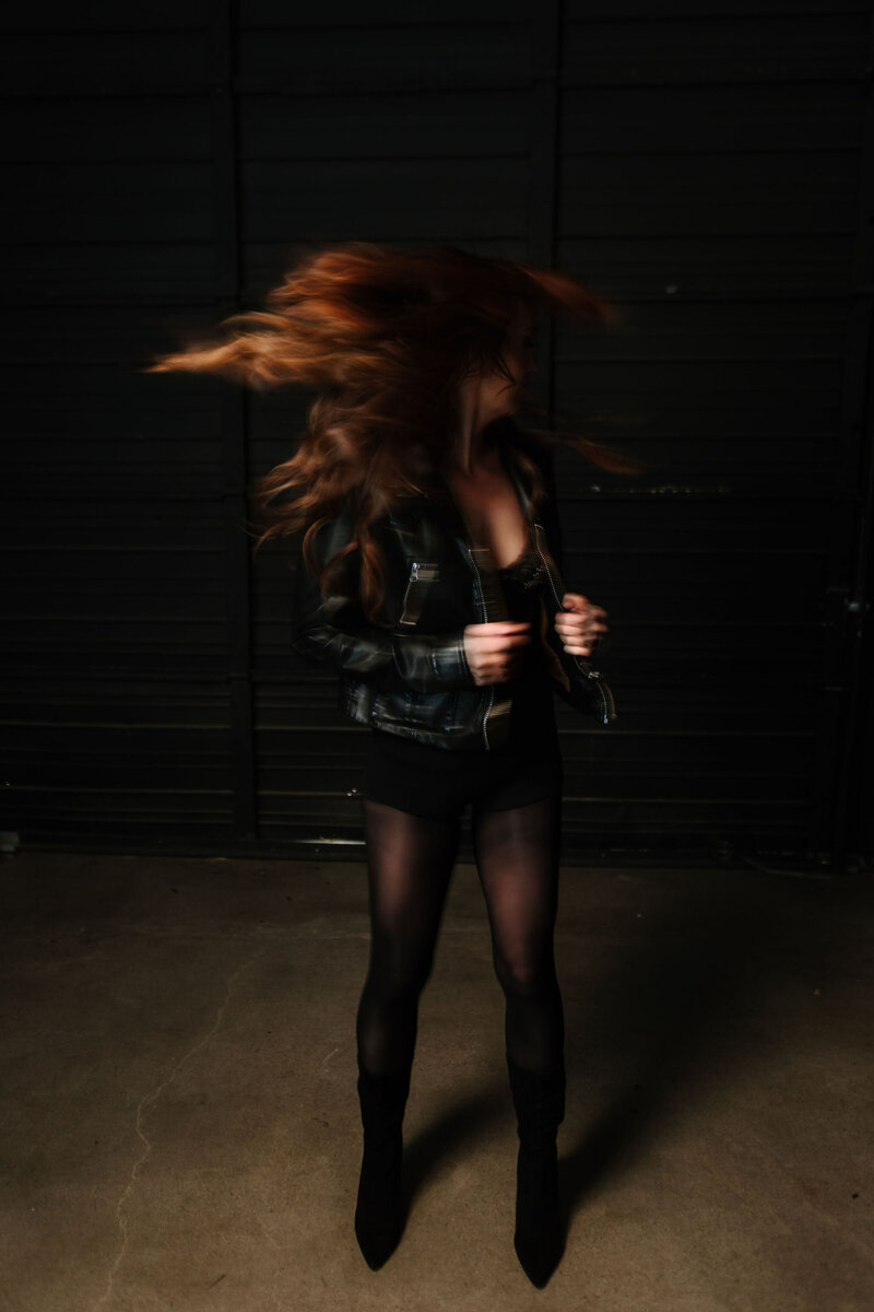 Photo of Juliet Trnka in a leather jacket, looking over shoulder, in movement, hair flipping