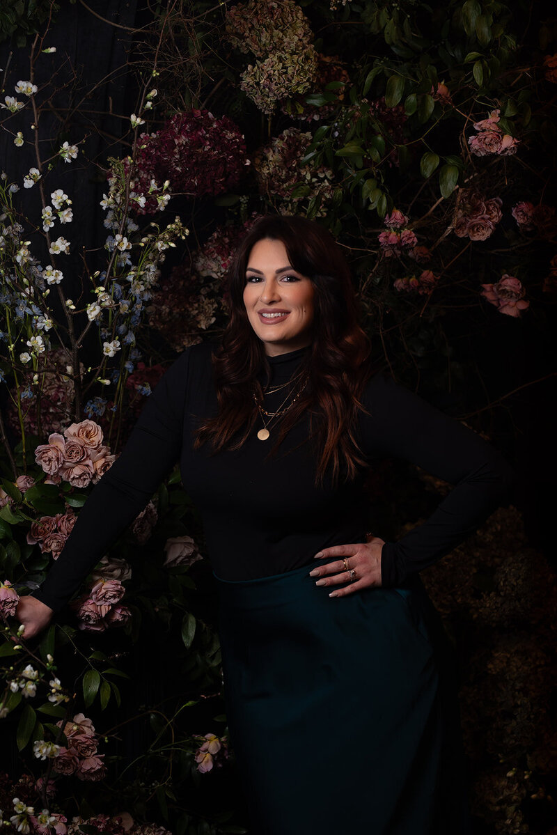 image of a woman against a black backdrop of mauve, burgundy and white flowers inspired by dutch masters paintings