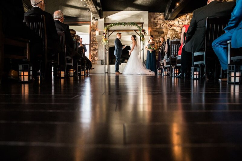 This intimate photograph captures the bride and groom reading their vows during a beautiful wedding ceremony at the Lake House, creating a heartfelt moment surrounded by nature.