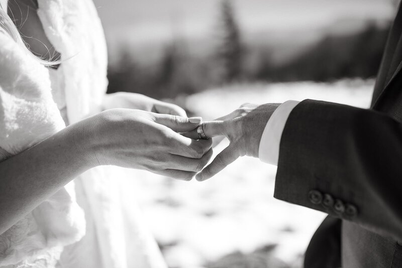 Image of a bride and groom's hands as the bride slips a ring on the groom's finger