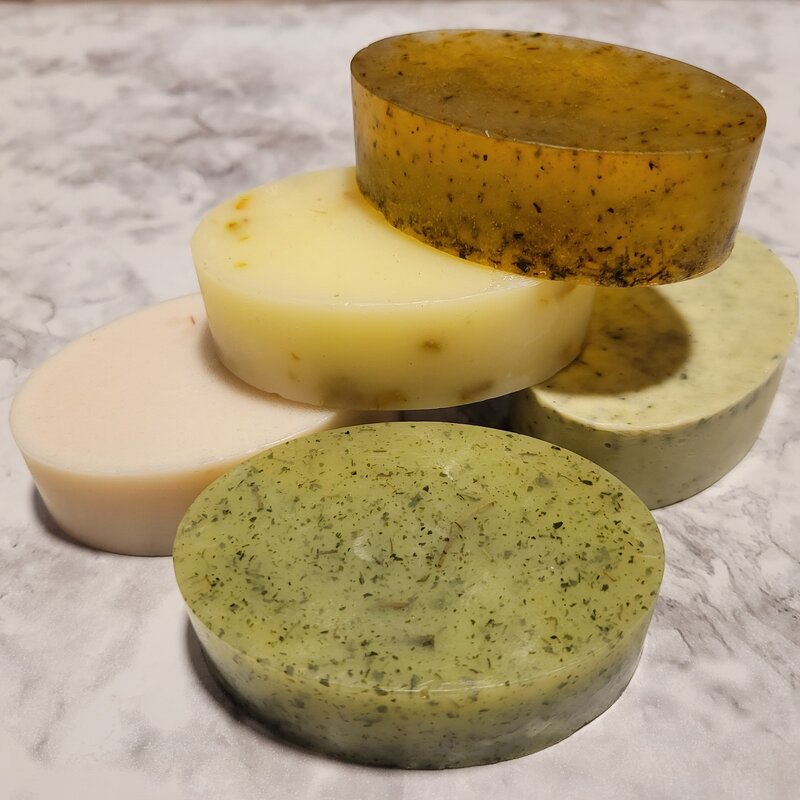 Stack of artisan soap bars including rosemary, lemon, and mint blends