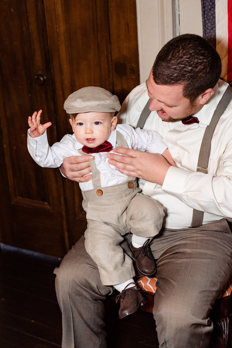 Groom holding his son and helping him get ready for the wedding day