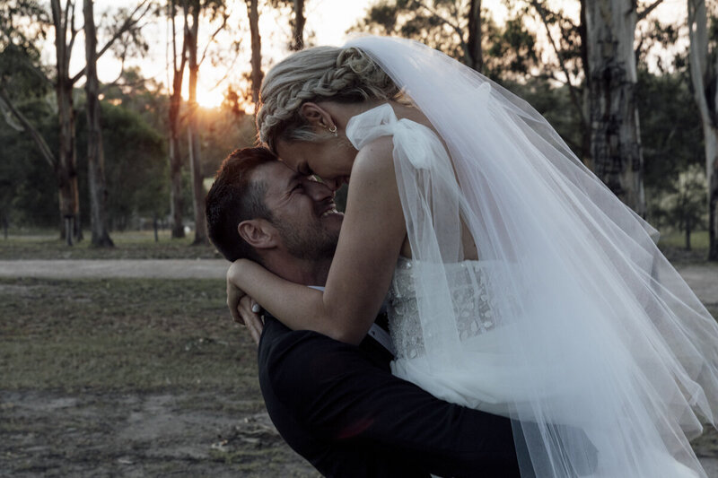A Bride and Groom having their Wedding photos taken at Eight Acres Lakes Entrance. The Bride is wearing a white dress and the groom is wearing 