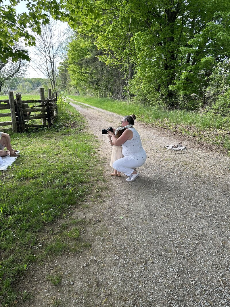 Candid behind-the-scenes moment between Denise and a young client, capturing magic together in nature.