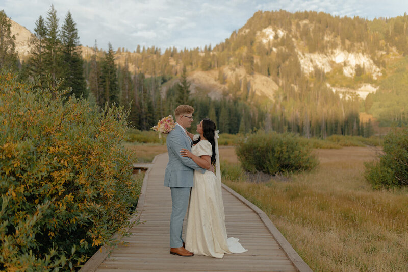 Wedding photography by Brittney Ann Photography. A bride and groom hold and look at each other with the mountains behind them.