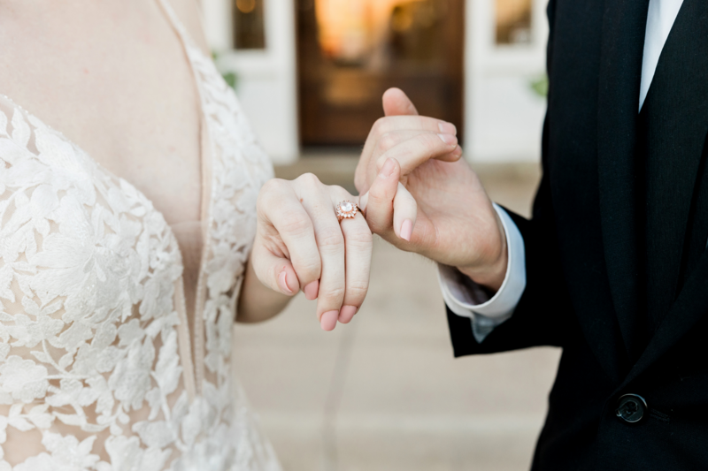 Heartwarming image of the bride and groom making a pinky promise, showcasing the bride's wedding ring, symbolizing their commitment and love on their special day.