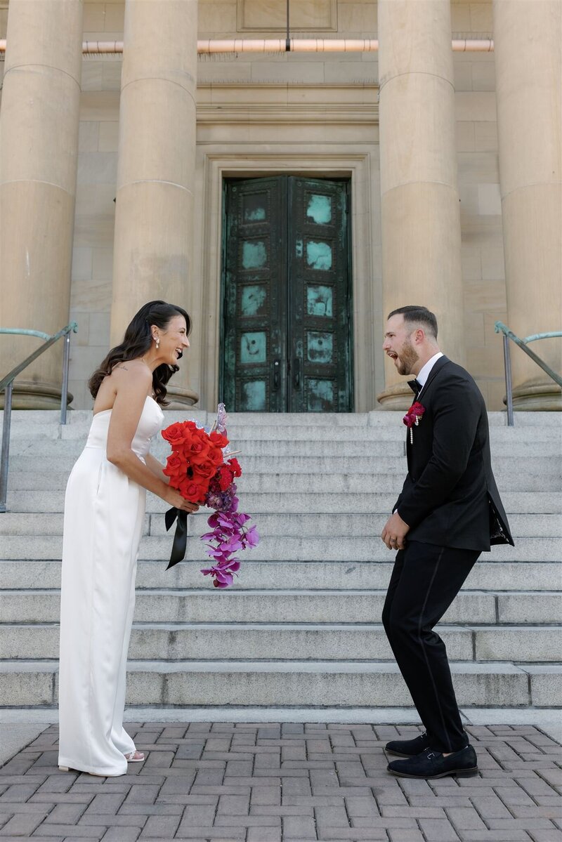 bride and groom first look facing one another in front of the Line Hotel in DC at the bottom of the steps with the groom gaping in awe at his smiling bride