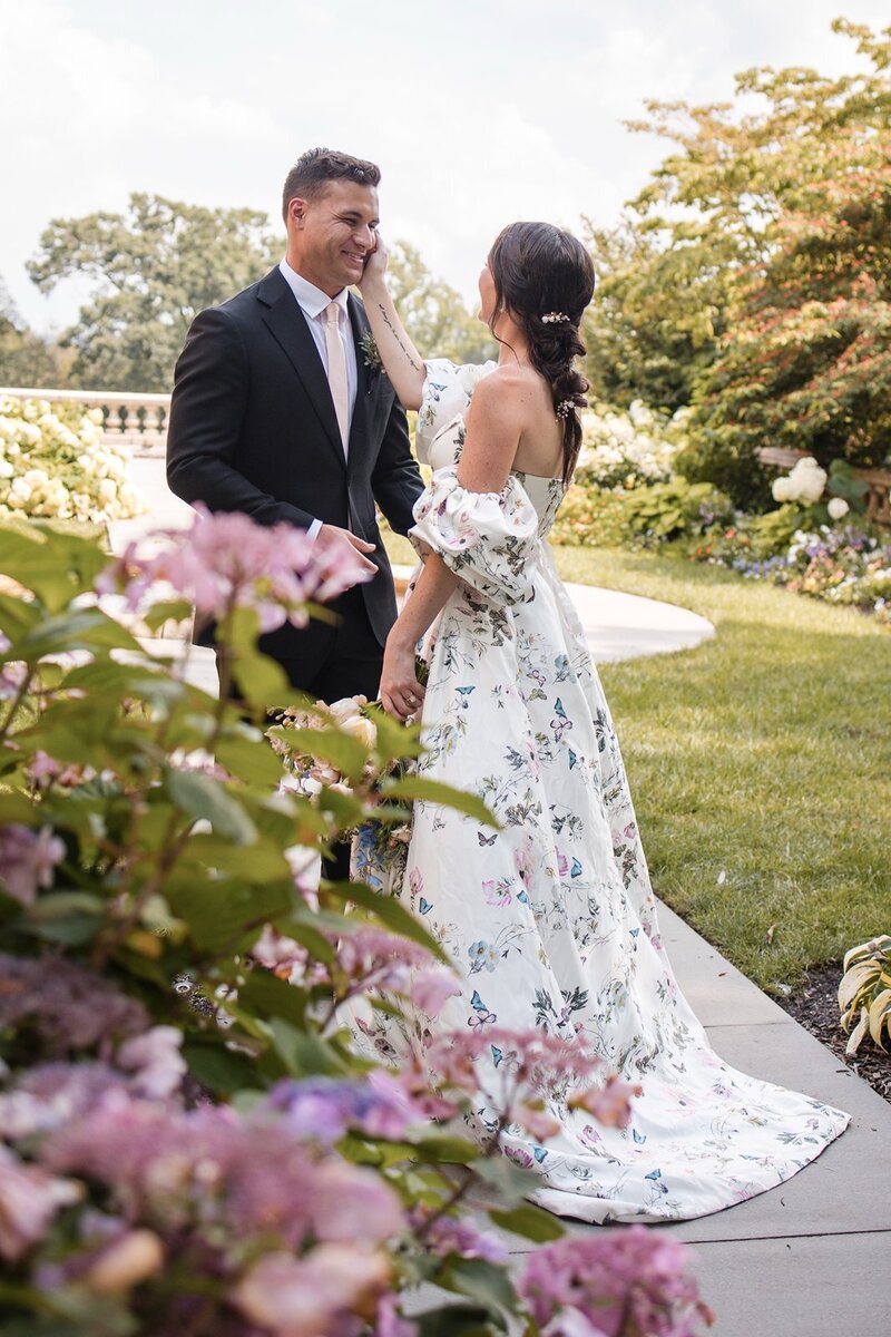 Bride in a whimsical butterfly wedding dress caressing her groom's cheek.