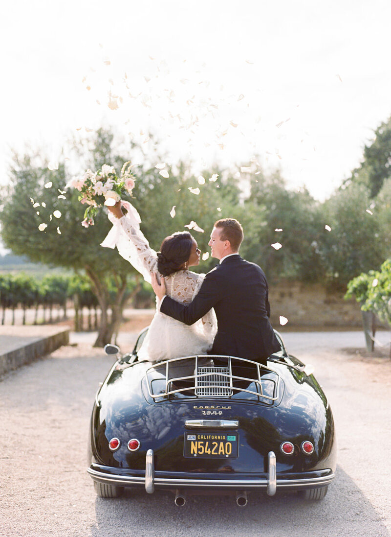 Bride and groom in black Porche at Sunstone Winery in California