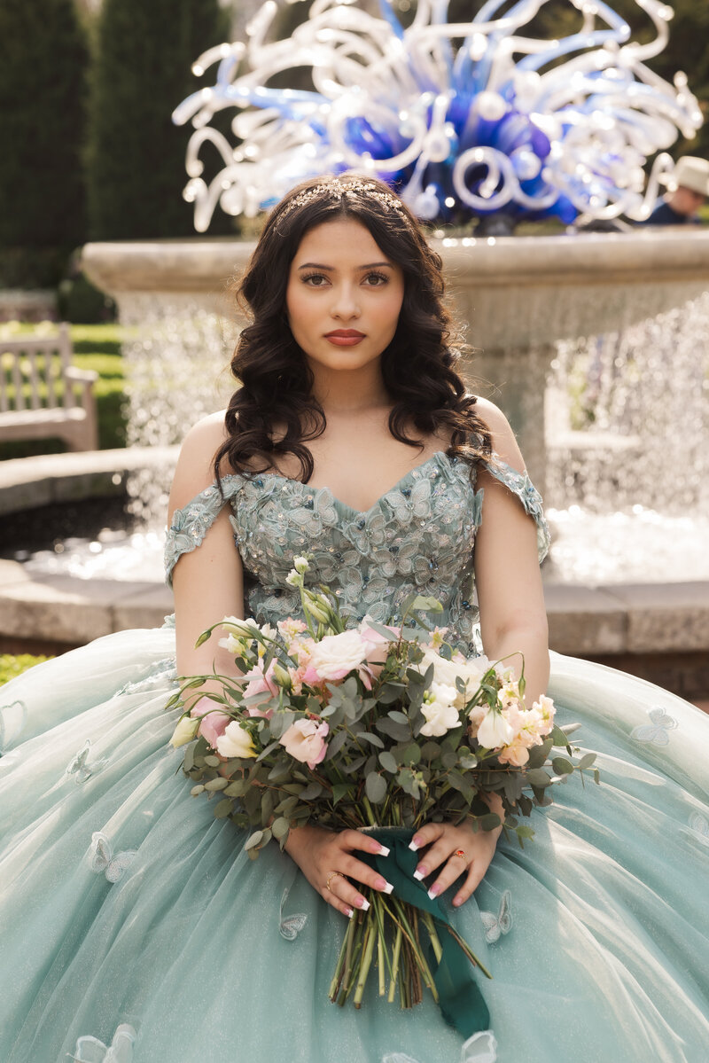 woman in quinceanera dress standing in front of large stone building