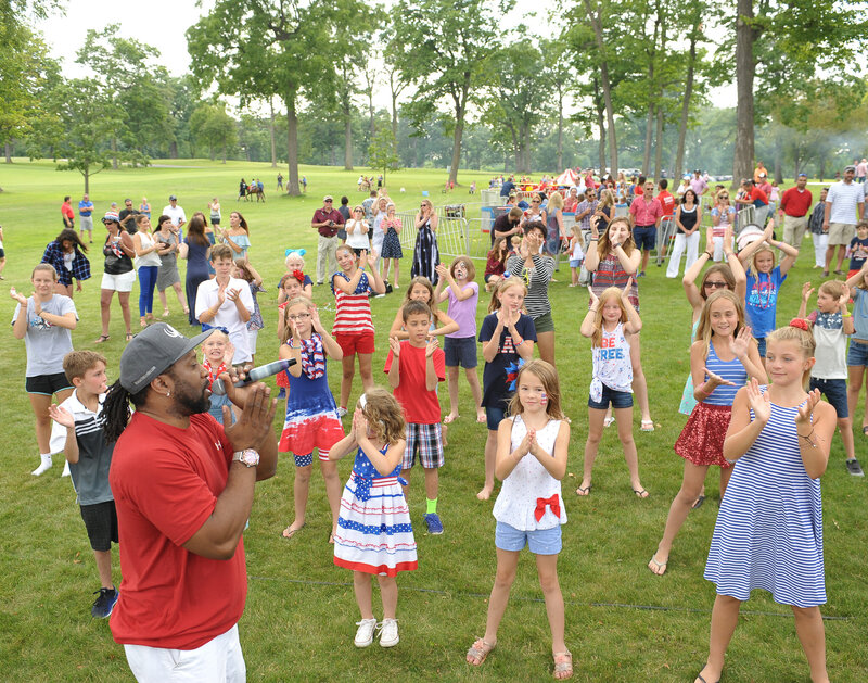 DJ leading kids in a dance at outdoor event