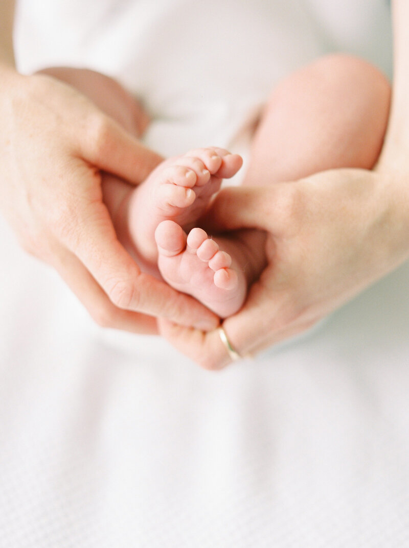 Close up of mom holding baby feet - Fika Newborn