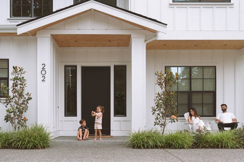 family of four at white house on porch