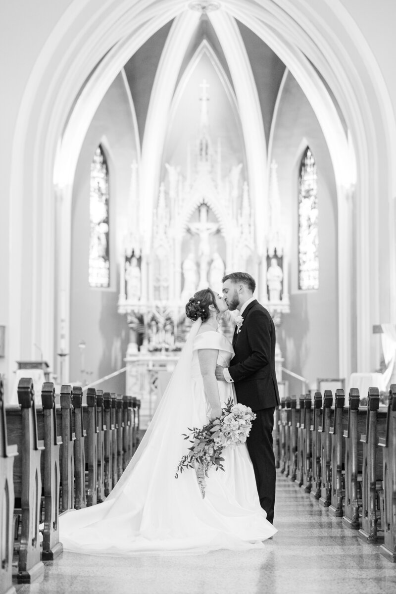 bride and groom kissing in the aisle of a church
