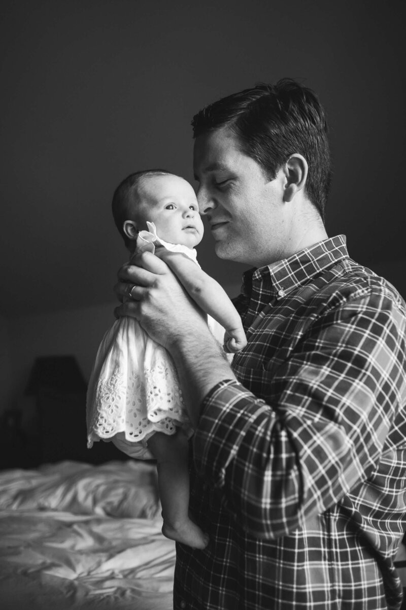 Baby girl in white dress with her dad in black and white