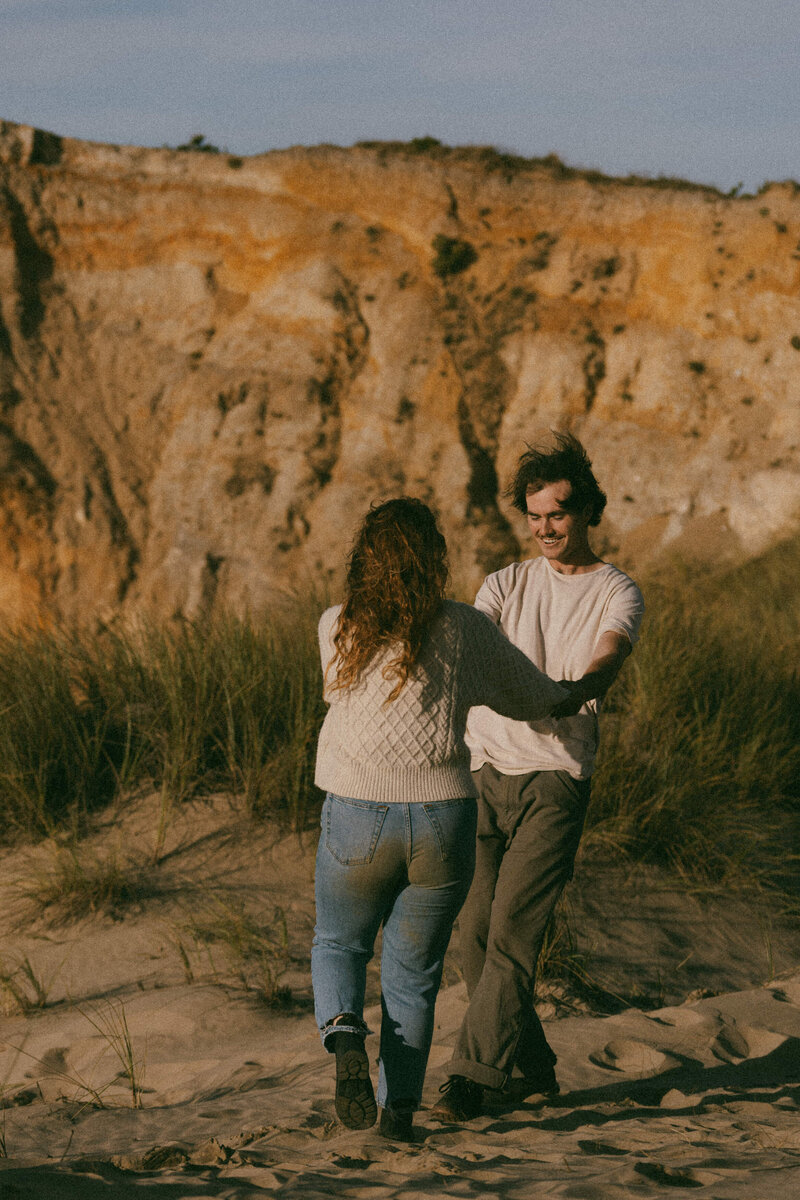 A person smiling at their partner as they hold their hands and spin in a circle 
