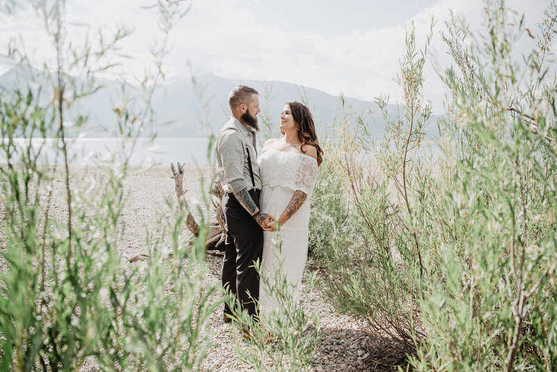 beach wedding int he mountains captured by jackson hole wedding  photographers with bride and groom holding hands and gazing at one another