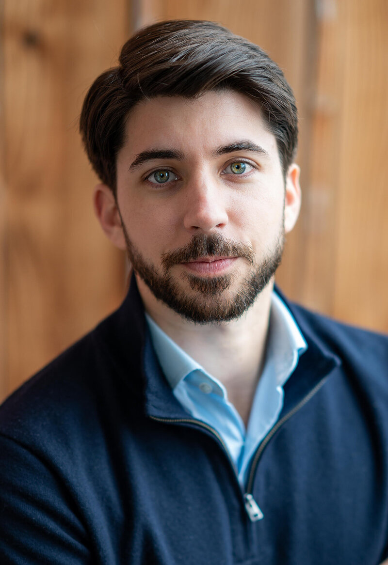 Professional headshot of a male model in San Francisco wearing a dark jacket, white t-shirt, and a gold chain