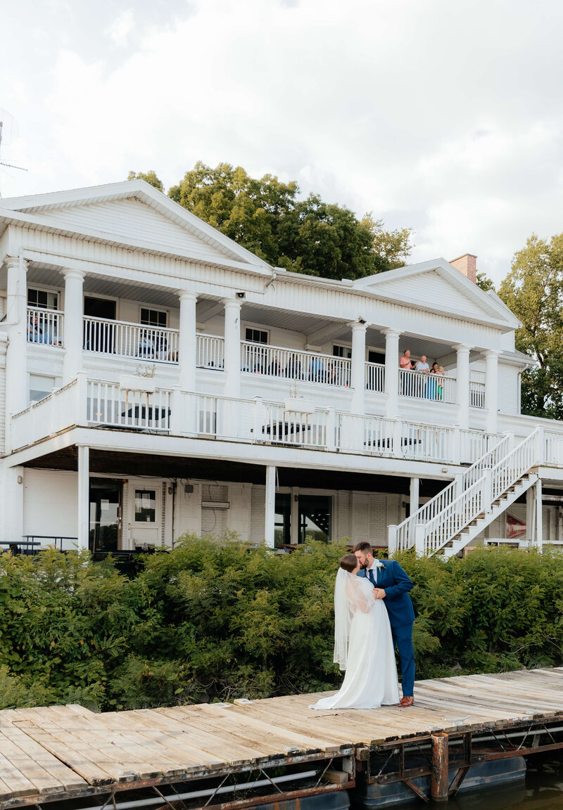 Modern Midwest couple in front of riverfront wedding venue, candid wedding photography full of warmth and real connection