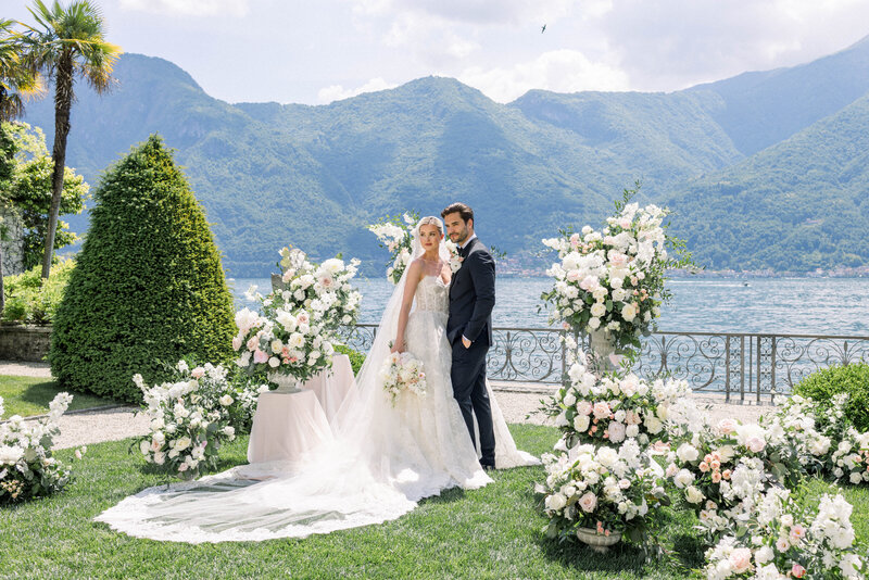 bride and groom embracing in large field with mountains in the background