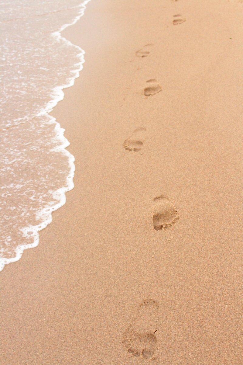 Footprints in sand next to the ocean