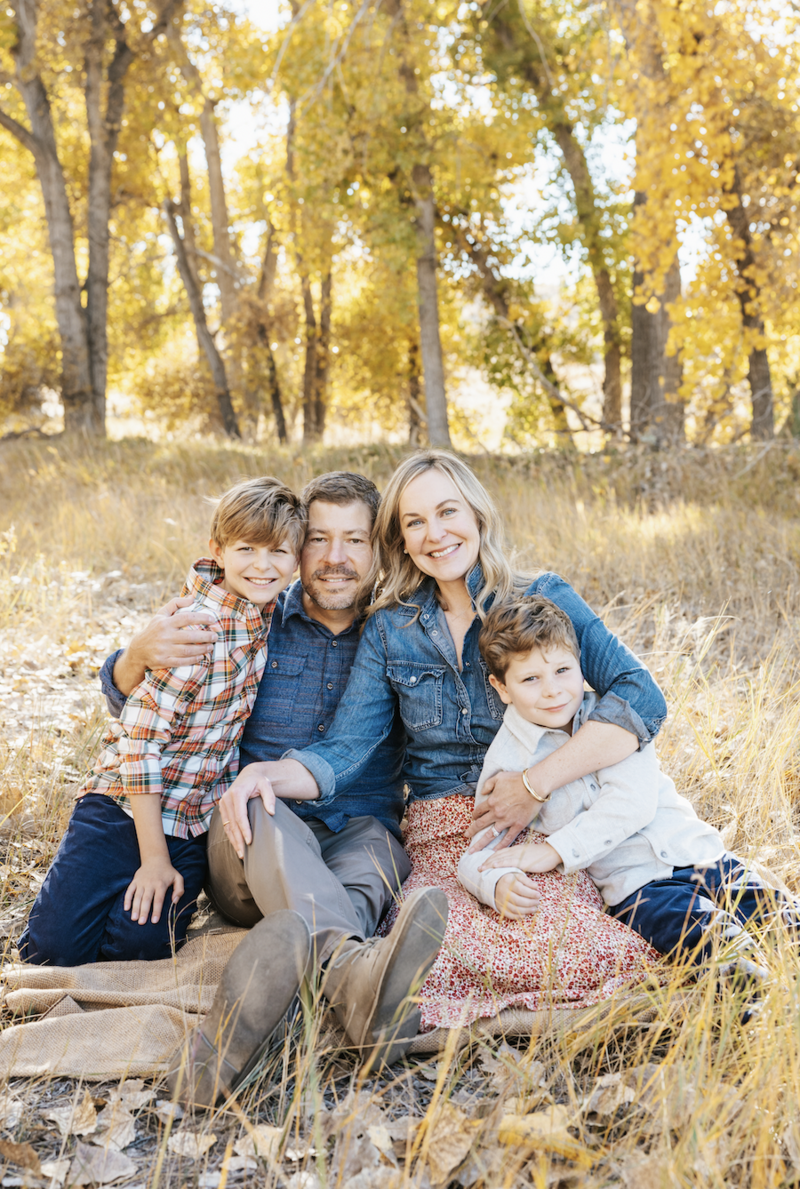 A person holding up an ultrasound image with another child, their partner, and a dog sitting next to them.