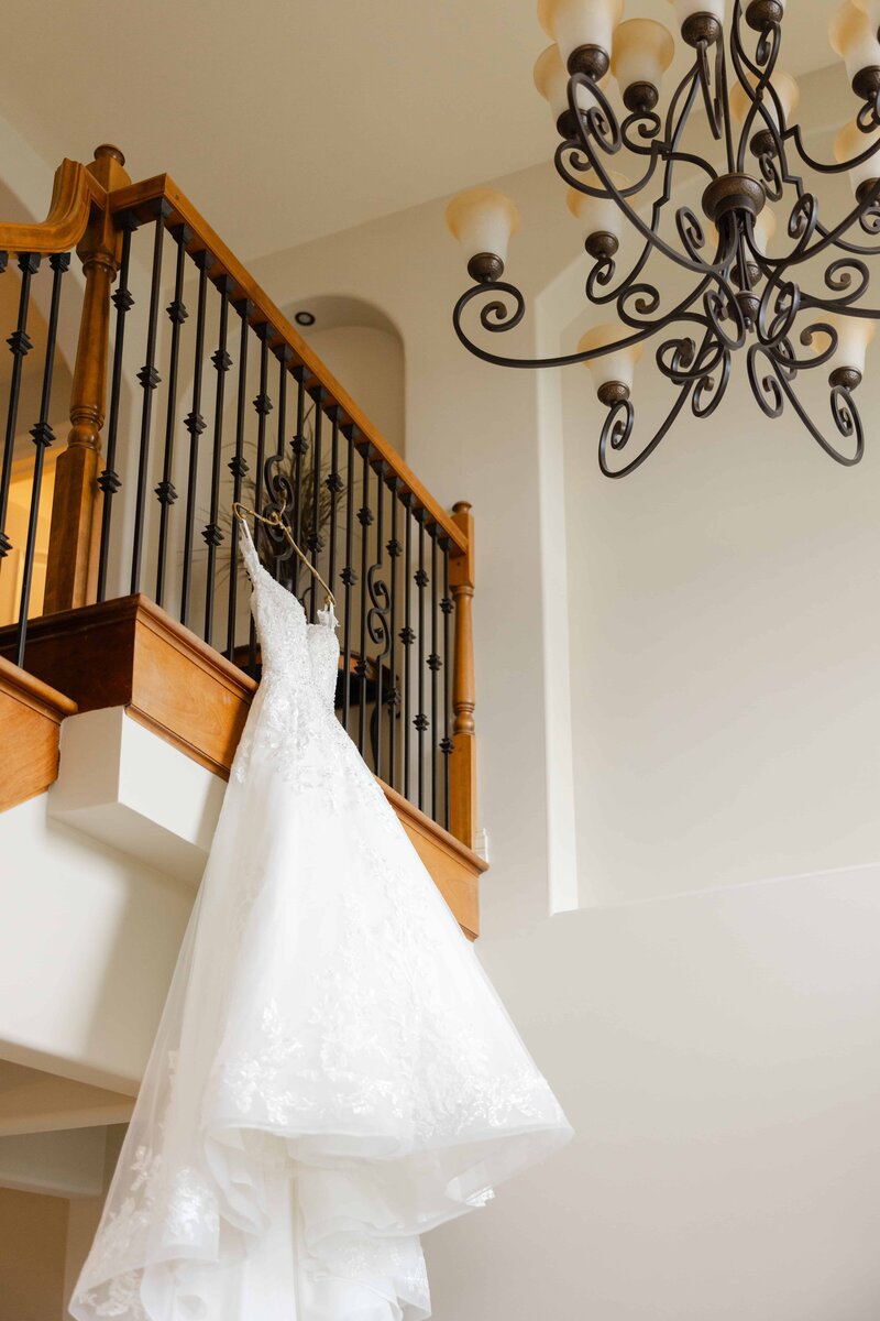 Bridal gown hanging from banister in brides home.