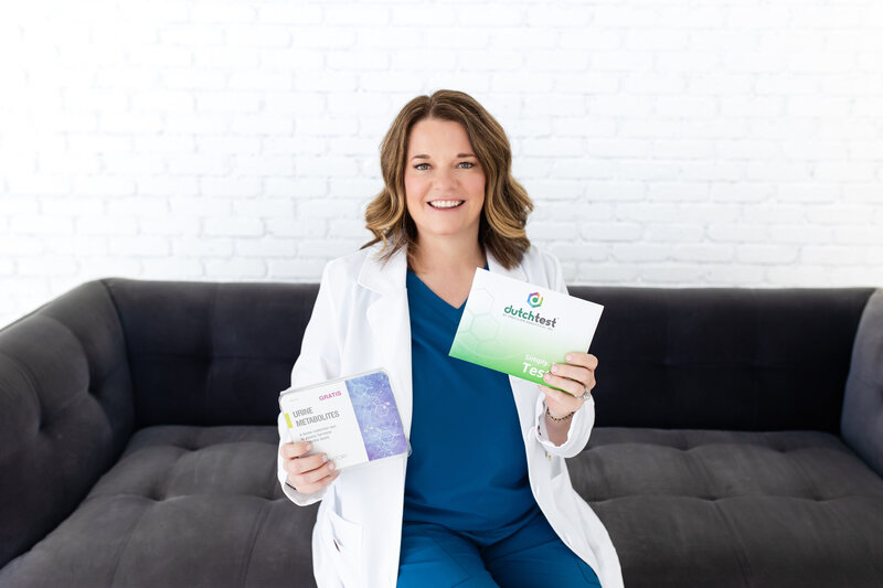 Meet our Hormone Optimization Program specialist, seated on a black couch in her blue nursing uniform, holding the best market products that ensure fast results thanks to her expertise