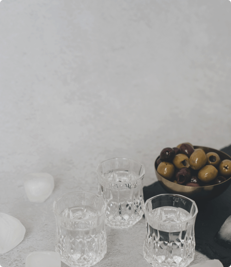 A display of glasses filled with water next to a metal bowl of assorted olives.