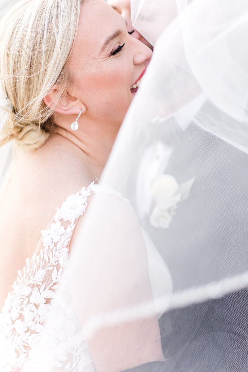 Bride smiling under veil in close-up portrait