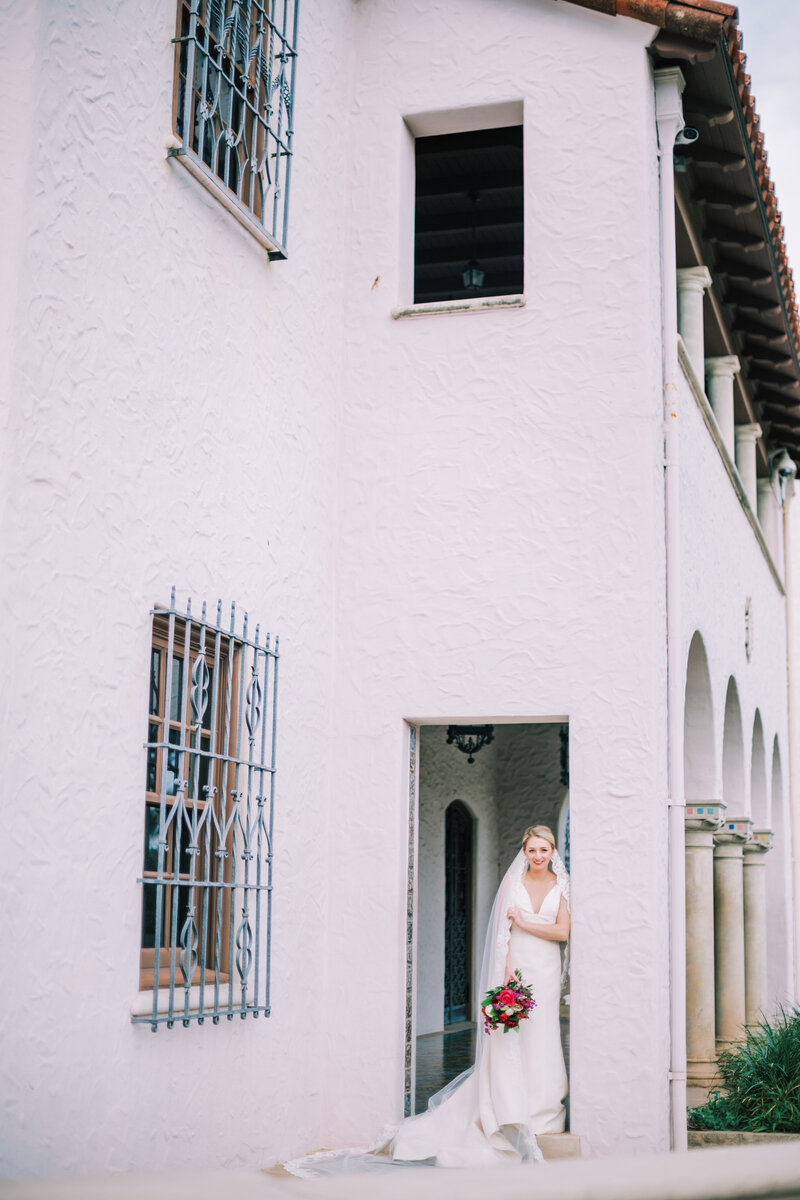 Bride standing in outside in a door frame against a large white building