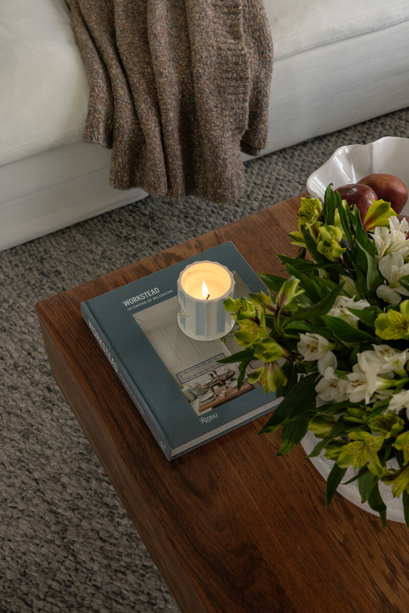 Extreme close-up of layered textured blankets and plaid pillows on a white sofa, highlighting cozy details, designed by Sister Studio.