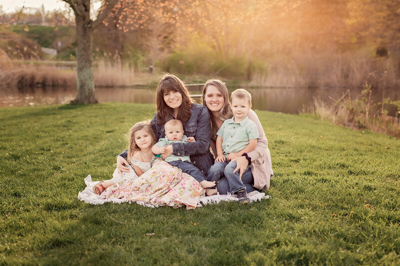Three generations family outside on blanket by water during sunset