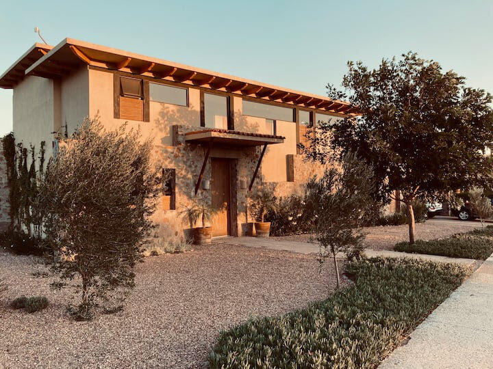 Front view of Casa Barragán in San Miguel de Allende, featuring stone walls, modern windows, and rustic landscaping