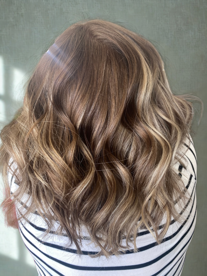 Professional stylist after shot of a blowout on wavy colored hair, enhancing scalp health and hair shine.
