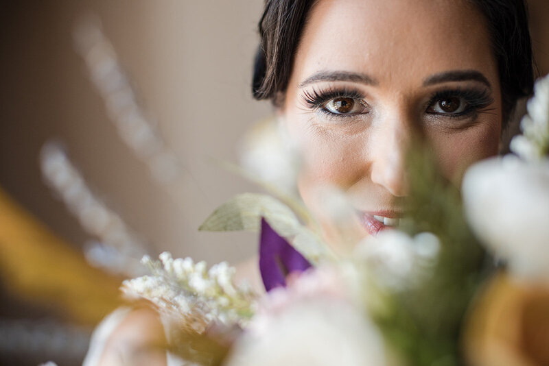 close up photo of a bride with brown eyes and long eyelashes, looking over her bouquet at her stonington ct wedding