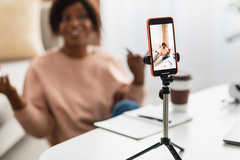 A confident Black woman creating video content for social media using her phone.