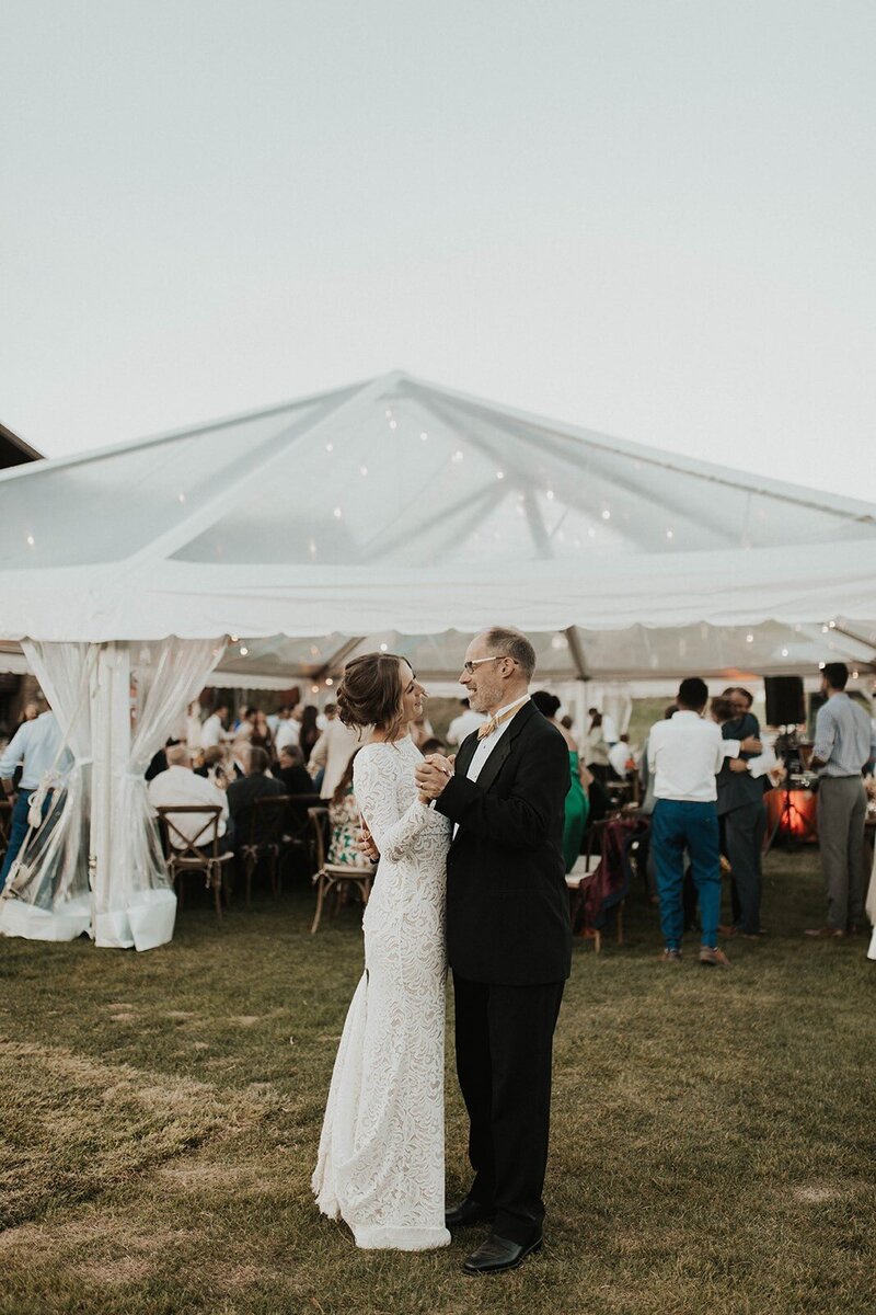 father dances with bride outside wedding reception tent