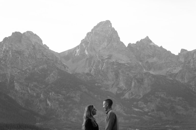 A couple silhouetted before the vast land leading to the Tetons.