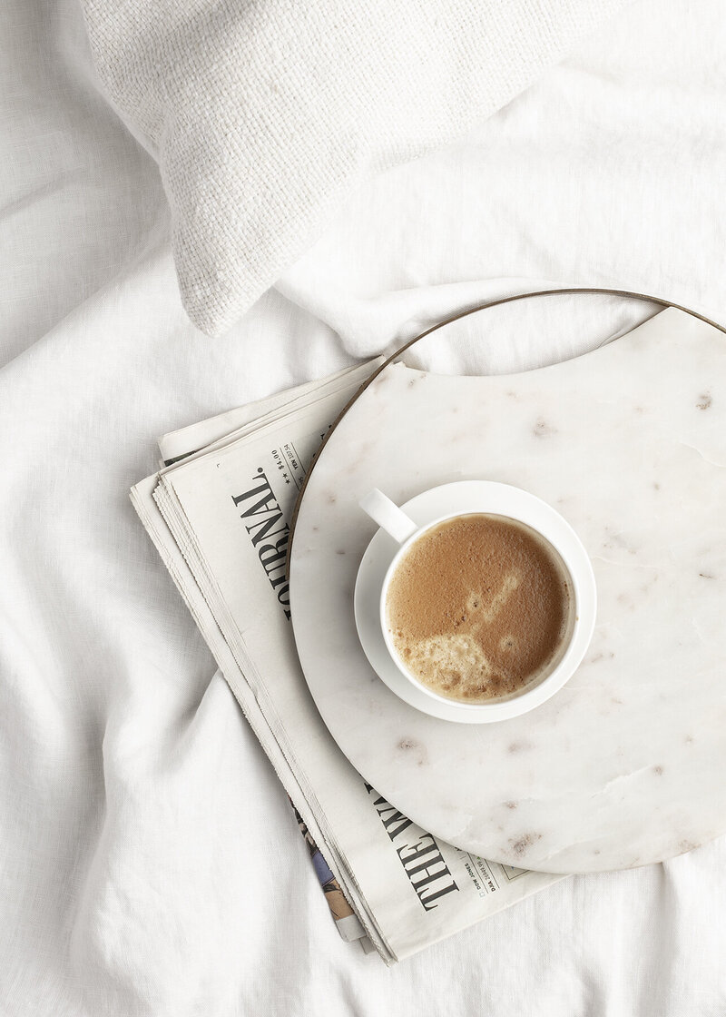 newspaper flat lay with coffee in bed