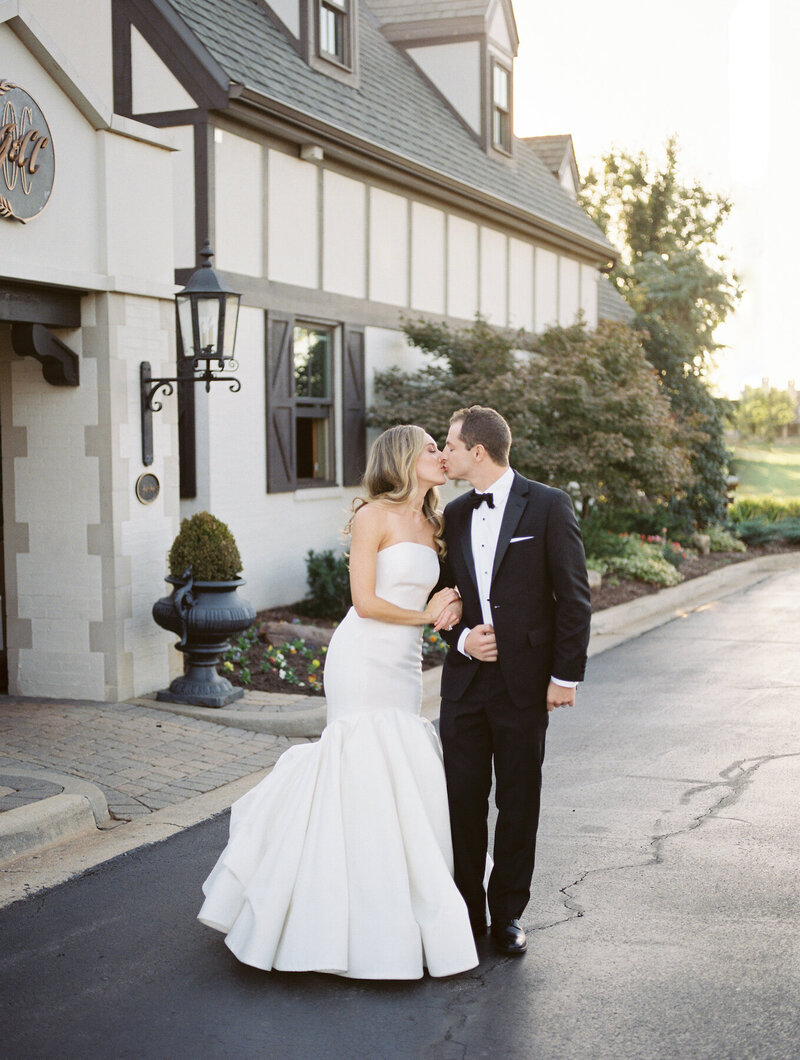 a bride and groom walking arm in arm kissing