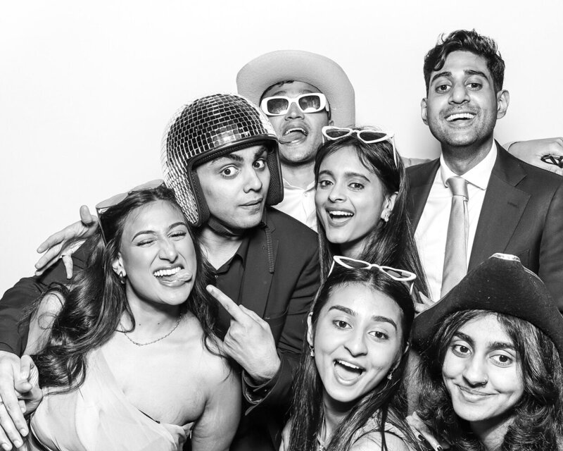 Black and white filter for a print with a large Asian family posing against a white backdrop, during a an Asian wedding party celebration, for Mad Hat Photo Booth