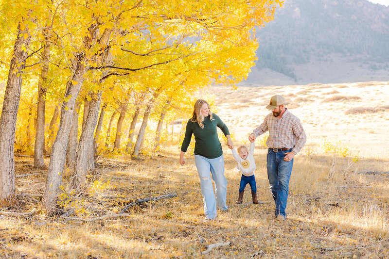 Mom and dad swinging their little girl during their family session at the Wild Horse Ranch near Laramie, Wyoming.