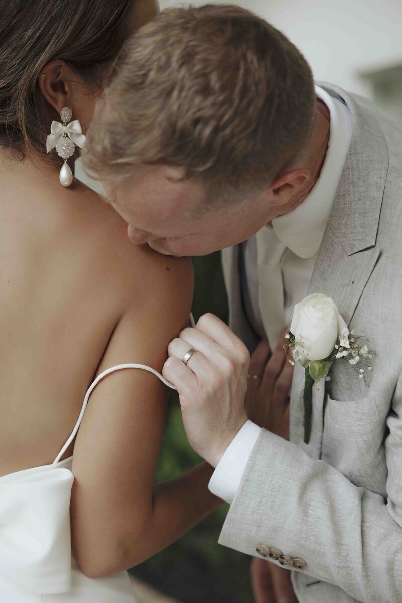 Groom kissing bride's shoulder