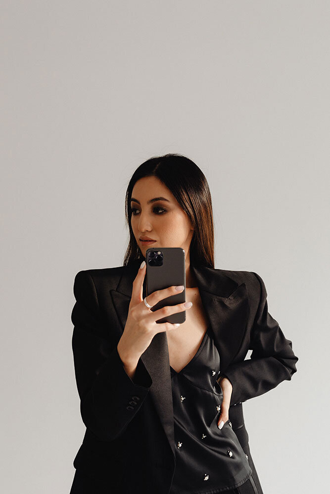 kaboompics_dark-classy-aesthetic-fashion-beautiful-asian-female-entrepreneur-in-black-suit-technology-and-devices-iphone-laptop-airpods-30096