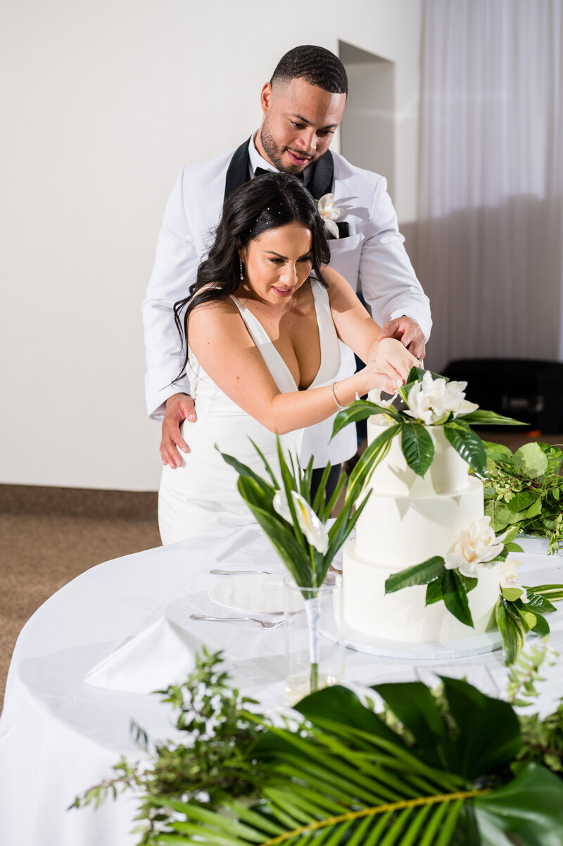 Bride and groom cutting their wedding cake by Las Vegas Custom Cakes during their reception at Emerald at Queensridge.